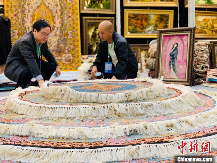 圖為參展商向咨詢的客商介紹地毯?!O睿 攝 圖為參展商向咨詢的客商介紹地毯?!O睿 攝